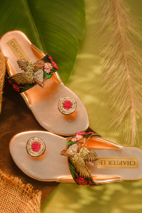 Pair of decorative sandals with floral and butterfly designs on a natural background